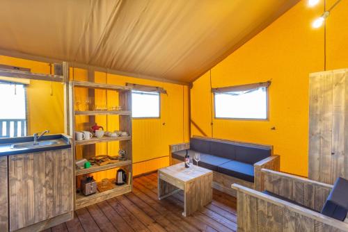 a yellow room with a blue couch and a table at Agriturismo Tenuta Regina - Glamping luxury lodges and apartments in Palazzolo dello Stella