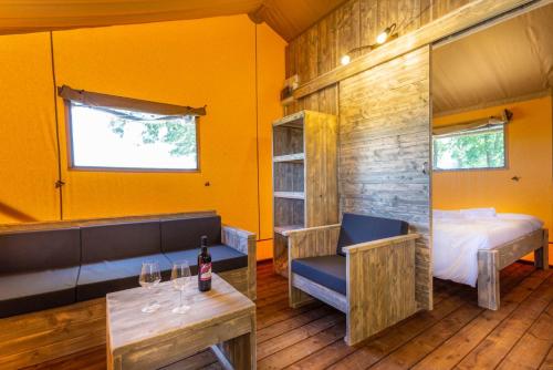 a room with a bed and a table with wine glasses at Agriturismo Tenuta Regina - Glamping luxury lodges and apartments in Palazzolo dello Stella