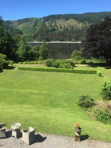 a large green field with benches and a lake at Dale Head Hall Lakeside Hotel in Keswick