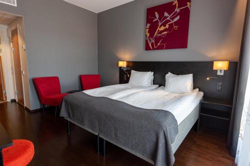 a bedroom with a large bed with two red chairs at Best Western Malmo Arena Hotel in Malmö