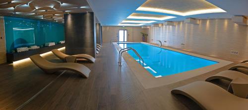 a swimming pool in a building with chairs and a swimming pool at Kronwell Brasov Hotel in Braşov