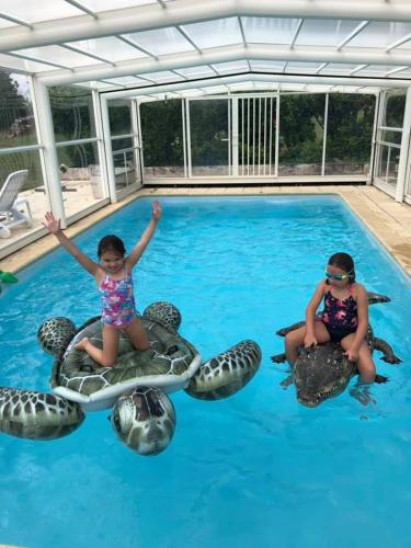 2 enfants assis sur des tortues dans une piscine dans l'établissement La Ferme De Montard, à Montmorot