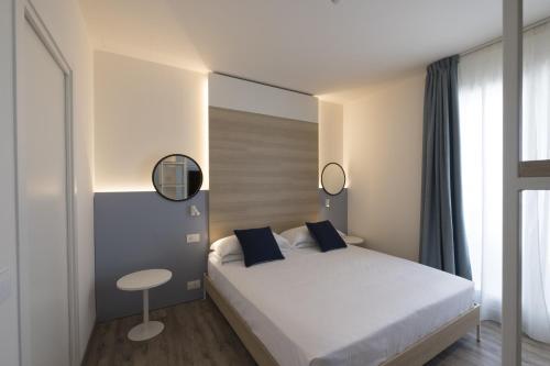 a bedroom with a white bed and a stool at Hotel Baia in Rimini