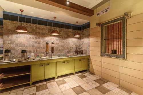 a kitchen with yellow cabinets and tile walls and a window at Budget Inn Bellevue in Surat