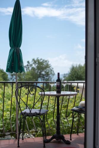 a table with a bottle of wine and chairs on a balcony at Apartments Tabain in Mlini