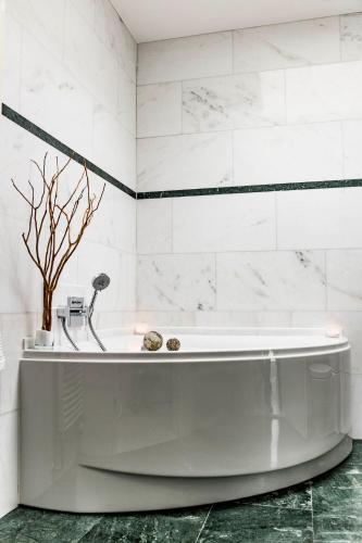 a white bath tub in a bathroom with white tiles at Dreamapartment La Vigna "Stone" Suite mit eigenem Indoorpool & Sauna & Grillhütte - Weil am Rhein in Weil am Rhein