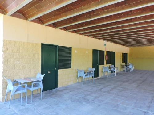 a room with chairs, tables, and benches at Hostal - Bungalows Camping Cáceres in Cáceres