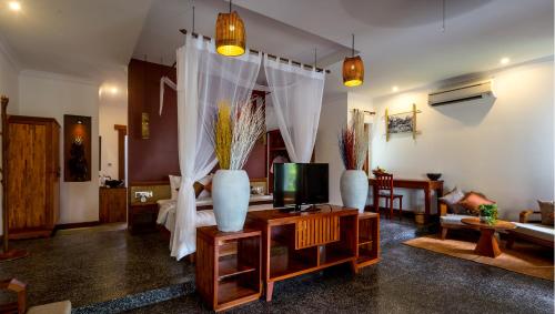 a living room with a tv and vases on a table at La Rivière d' Angkor Resort in Siem Reap