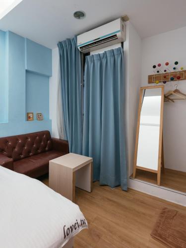 a bedroom with a bed and a couch and a mirror at Fengjia Love I Hostel in Taichung