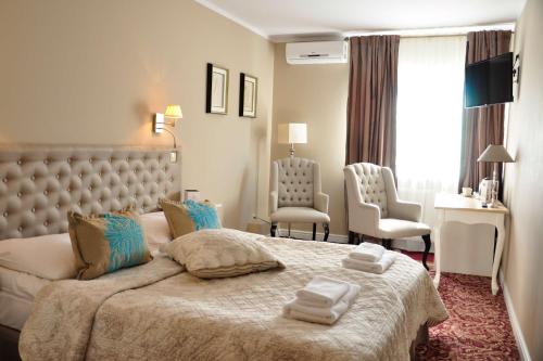 a bedroom with a large bed and two chairs at Riviera Resort Airport Modlin in Olszewnica Nowa