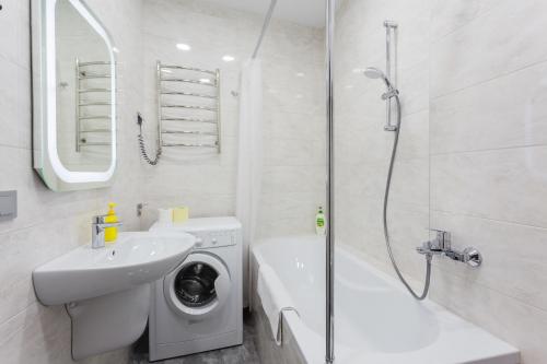 ein weißes Badezimmer mit einer Waschmaschine und einem Waschbecken in der Unterkunft Апартаменти Герцена 35 in Kiew