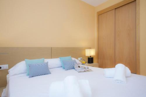 ein Schlafzimmer mit einem großen weißen Bett mit blauen Kissen in der Unterkunft SingularStays Moncofar Beach in Moncófa