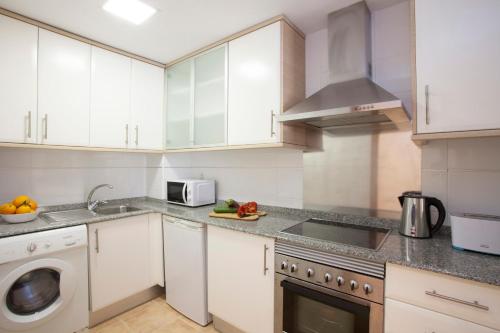 a kitchen with white cabinets and a sink and a dishwasher at SingularStays Moncofar Beach in Moncófar