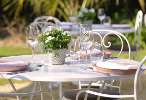 a white table with wine glasses and flowers on it at Chateau La Cheneviere in Port-en-Bessin-Huppain