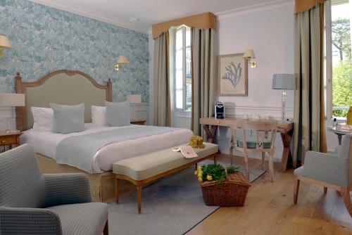 a bedroom with a bed and a table and chairs at Chateau La Cheneviere in Port-en-Bessin-Huppain