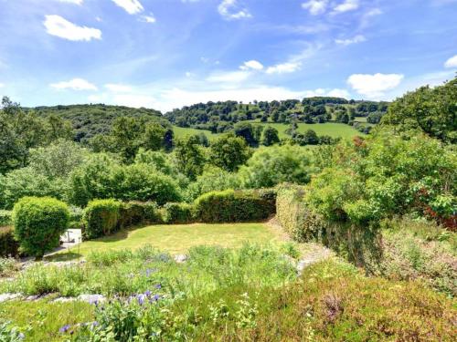 Llansantffraid Glyn CeiriogにあるHoliday Home Dolywern by Interhomeの花と木々の庭園を望む