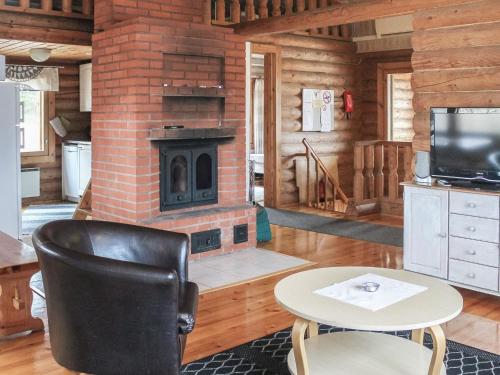 a living room with a fireplace and a table and chair at Holiday Home Kalliokoivu by Interhome in Torvoila