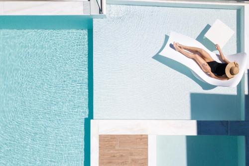 a woman laying on a chair next to a swimming pool at Wave Villa, Seaside Living & Your Own Beach Spot, By ThinkVilla in Panormos Rethymno