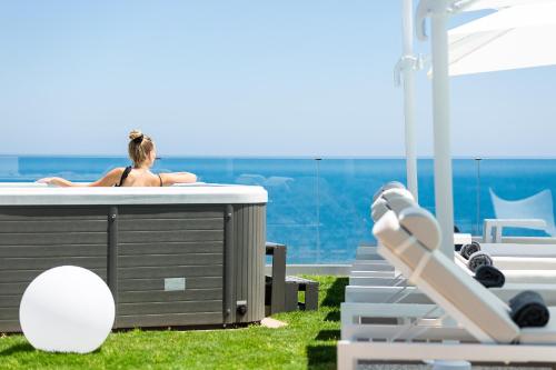 Una mujer sentada en un jacuzzi junto a una playa. en Wave Villa, Seaside Living & Your Own Beach Spot, By ThinkVilla, en Panormos Rethymno