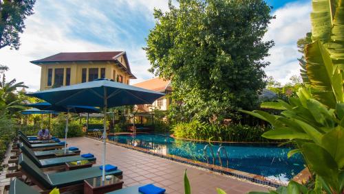 a pool at a resort with chairs and an umbrella at La Rivière d' Angkor Resort in Siem Reap