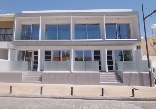 a large white building with glass windows at Shalos Studios in Ayia Napa