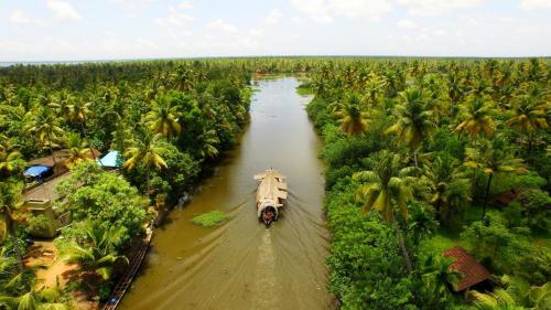 an aerial view of a boat in a river with palm trees at Spice Coast Cruises - Houseboat, A CGH Earth Experience in Alleppey