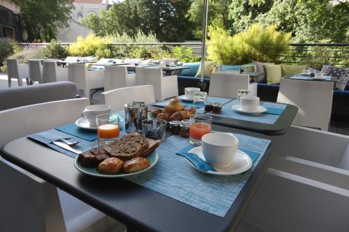 a table with a breakfast of coffee and pastries at Hotel De France in Valence