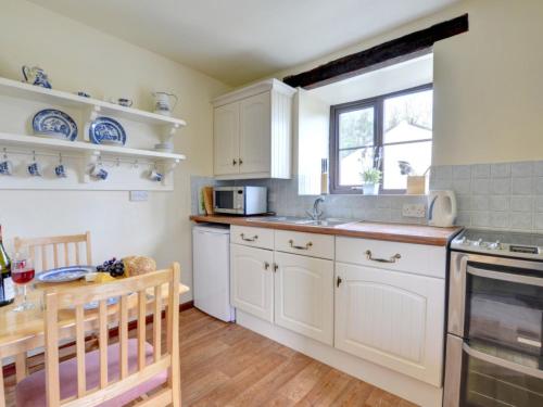 LlanerchymeddにあるHoliday Home Llanerchymedd-5 by Interhomeの白いキャビネット、シンク、テーブル付きのキッチンが備わります。