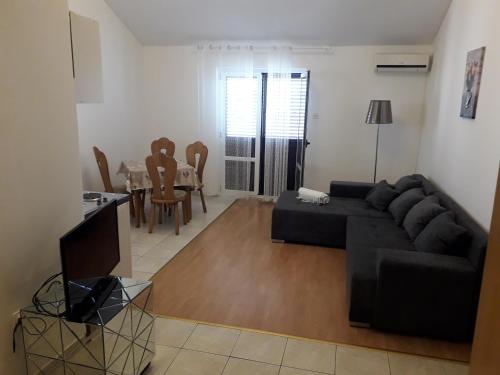 a living room with a black couch and a table at Apartments Dalmacija in Podstrana