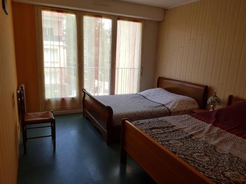 1 Schlafzimmer mit 2 Betten, einem Stuhl und Fenstern in der Unterkunft Royan plage in Royan