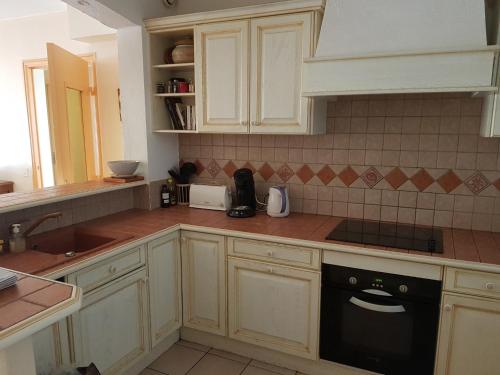 une cuisine avec des armoires blanches et un lave-vaisselle noir dans l'établissement Royan plage, à Royan