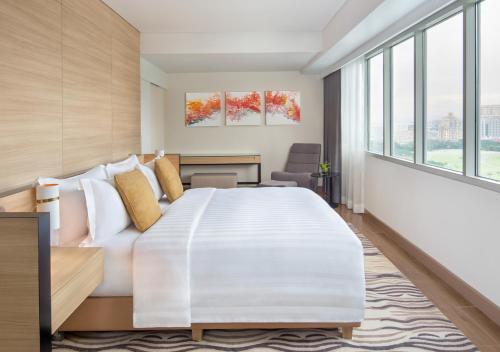 sypialnia z dużym białym łóżkiem i dużymi oknami w obiekcie Brittany Hotel BGC w mieście Manila