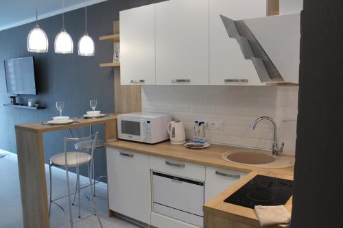 a kitchen with white cabinets and a microwave at Apartment on Bratskaya 6 in Minsk