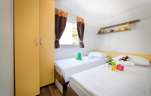 two beds in a room with yellow and white at Holiday Resort Medveja - by Liburnia Hotels & Villas in Medveja