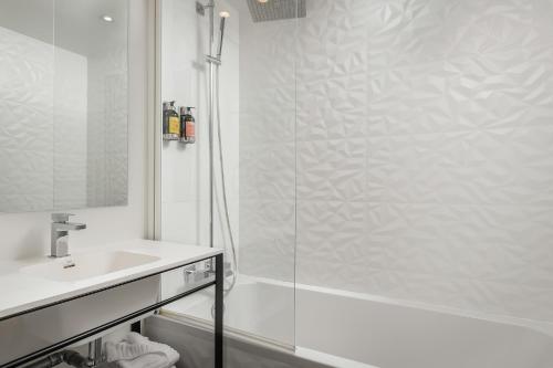 a white bathroom with a shower and a sink at Arc De Triomphe in Paris