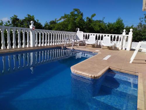 a swimming pool with chairs and a white fence at Holiday Home LaCerca in Icod de los Vinos