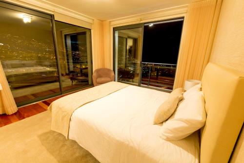 a bedroom with a white bed and a large window at Villa Beausoleil by Madeira Sun Travel in Funchal
