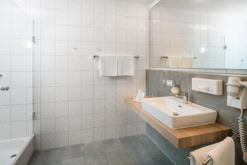 a white bathroom with a sink and a bath tub at Ringhotel Reubel in Zirndorf