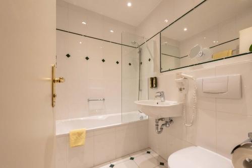 a bathroom with a sink and a tub and a toilet at Hotel Vollmann in Weilheim in Oberbayern