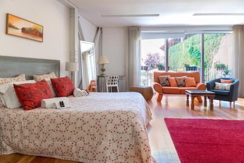 a bedroom with a bed and chairs and a large window at Capim Dourado Apartments Cedofeita in Porto