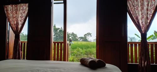 a room with a bed and a window with a view of a field at Villa Sindoro Village in Wonosobo