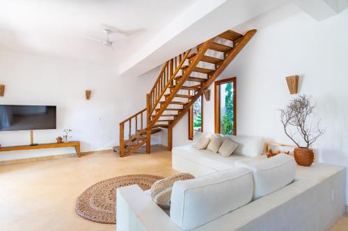 a living room with a white couch and a staircase at CasaLô Hotel in Jericoacoara