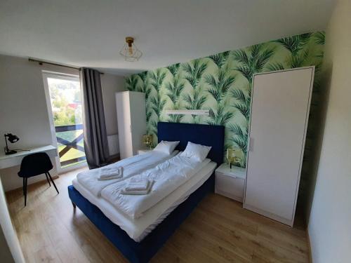 a bedroom with a large bed with a tropical wallpaper at Apartamenty Piano in Świeradów-Zdrój