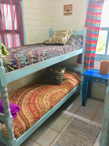 two bunk beds in a room with a table at CasaHostel Floresce in Praia do Rosa