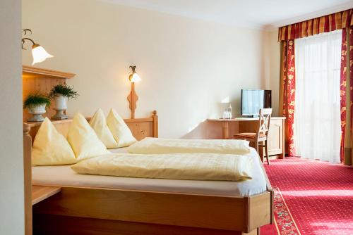 a bedroom with a bed and a desk with a computer at Landhotel Untermüllnergut in Dorfgastein