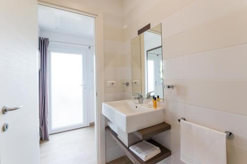 a white bathroom with a sink and a mirror at Torre Cintola Greenblu Sea Emotions in Monopoli