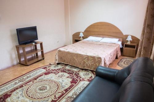 a bedroom with a bed and a tv and a couch at Fatima Hotel in Kazan