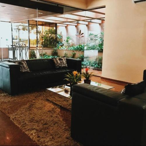a living room with black leather couches and plants at London Class Hotéis in Sao Paulo