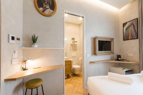 um pequeno quarto com uma cama, uma secretária e uma casa de banho em Duomo Deluxe Room em Milão