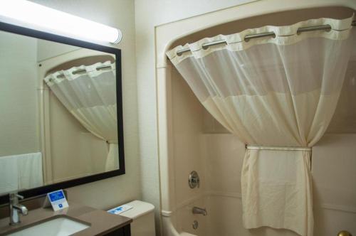 a bathroom with a shower curtain and a mirror at Comfort Inn in Lévis